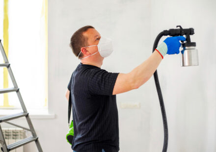 Man painting wall with sprayer