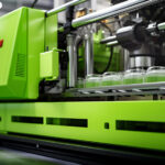 close-up image of a green plastic injection molding machine